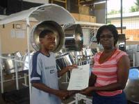 Stefan Hosten being presented his certificate with distinction, by steelpan tutor Adelle Joseph of birdsong Steel Orchestra