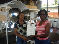 Derrianne Dyett is being presented her certificate with distinction by steelpan tutor Adelle Joseph of birdsong Steel Orchestra