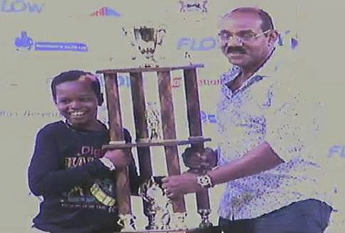 Young Halcyon Steel Orchestra player, holds trophy with Antigua-Barbuda Prime Minister Gaston Browne, at right
