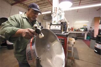 Cliff Alexis hammers a steel pan drum in his workshop. Alexis makes the drums used by the acclaimed NIU Steel Pan Band from old oil drums