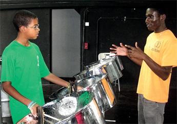Camper Solomon Dixon of the Pan in the Plaza Steel Pan Camp taking instructions from Christopher Belgrave during a lunchtime practice session at the Queens Park Steel Shed. Now in its eleventh year, the camp is hosted by the Central Bank of Barbados and the National Cultural Foundation (NCF) and will end with a Youth Pan Extravaganza on Saturday at the Cathedral Plaza.